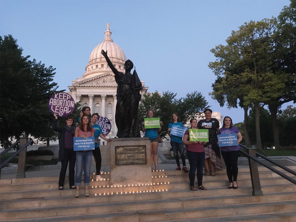 a group of activists on the steps surround a status at WI's capital