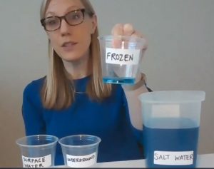 Carol holds up a cup of water labeled 'Frozen'