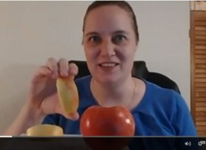 Laura holds up an apple slice to the screen.