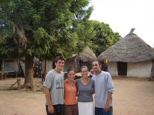 John, Laura, Marian, and Alex stand in front of a tree and a house.