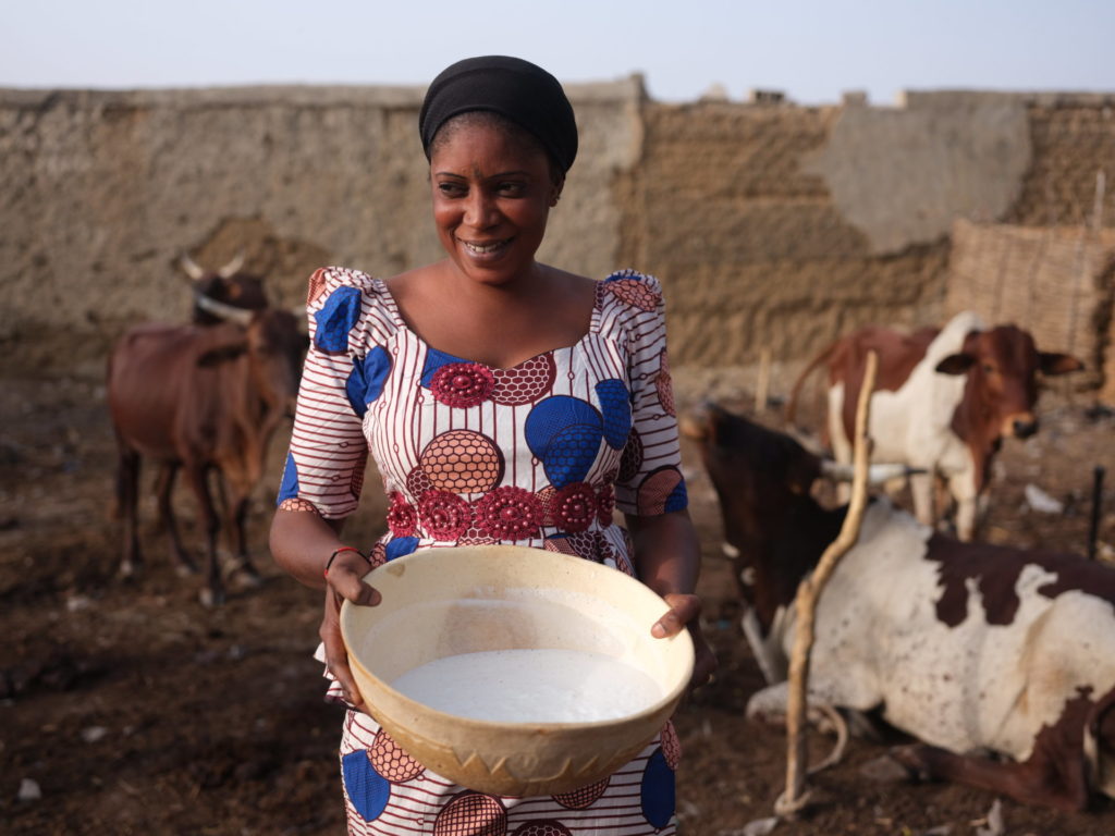 a Black woman smiles in front of her cattle