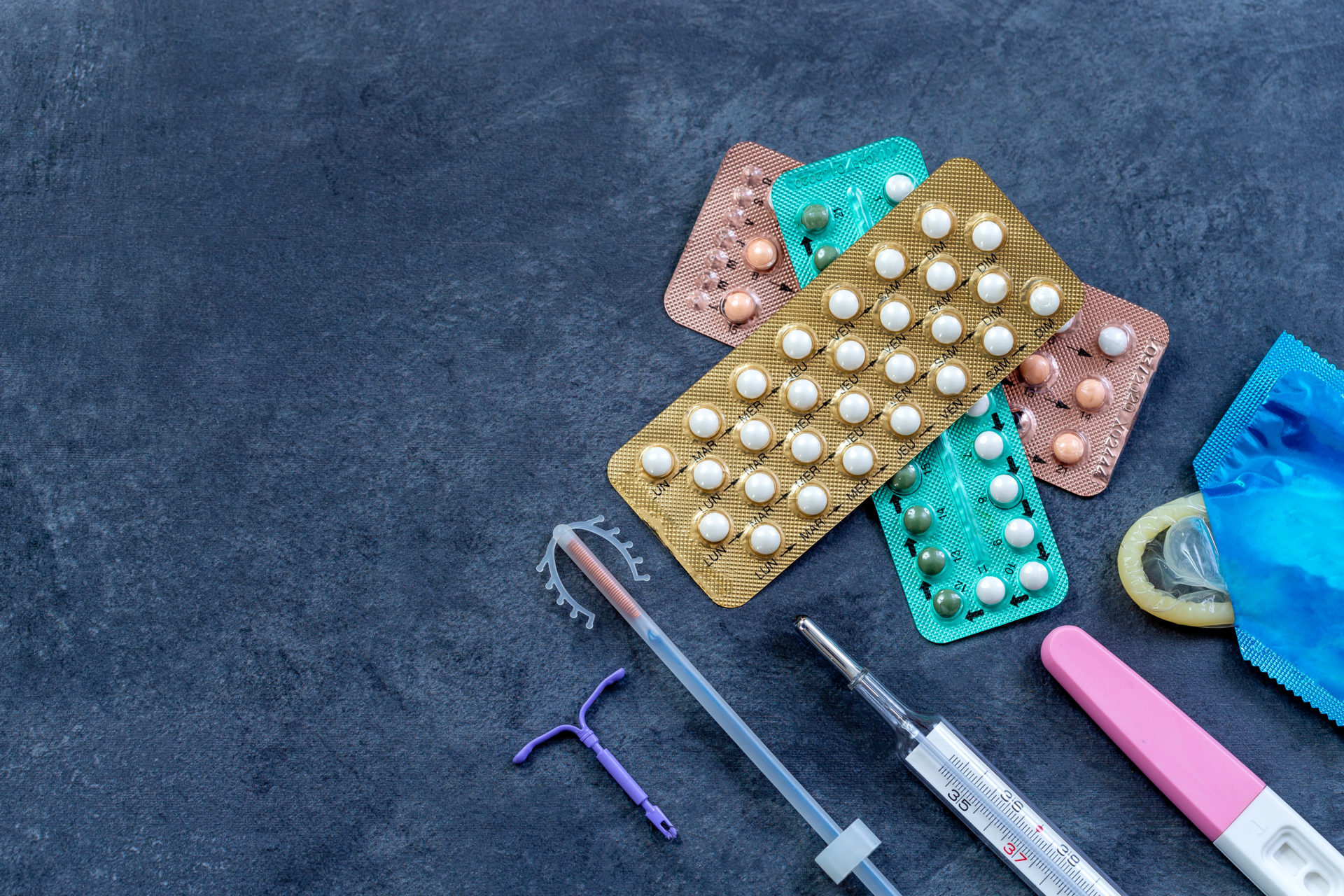 Picture of different contraceptive methods: birth control pills, an injection syringe and condom, IUD. Adobe Photos
