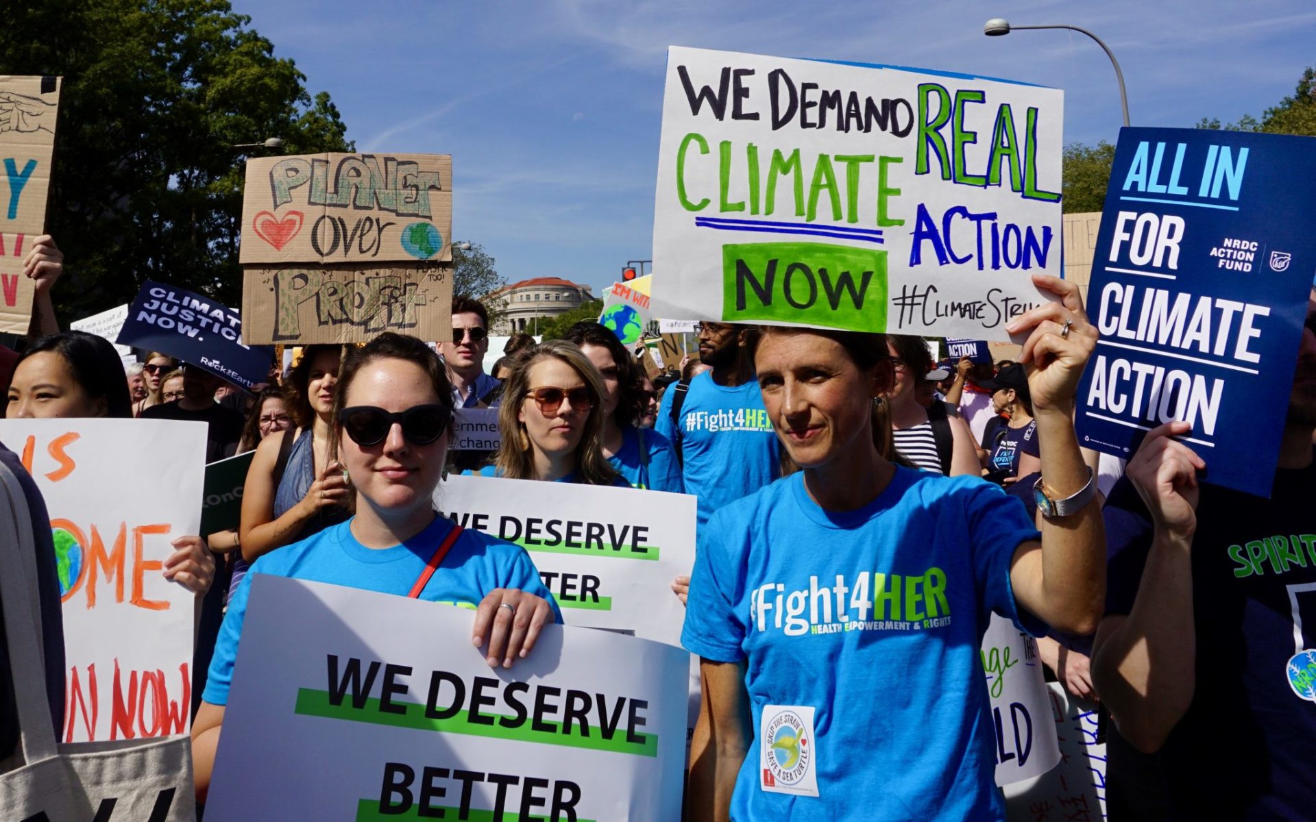 A group of young demonstrators holding signs while marching at a climate change rally