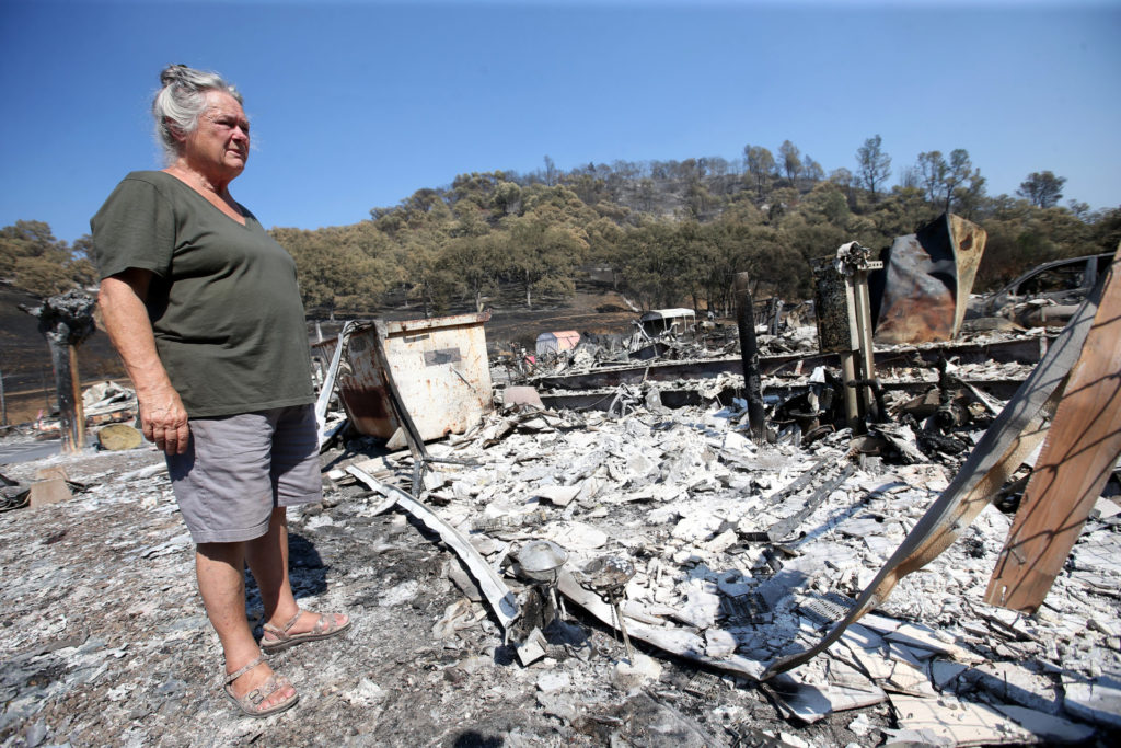 a woman stands over fire burned remains of buildings