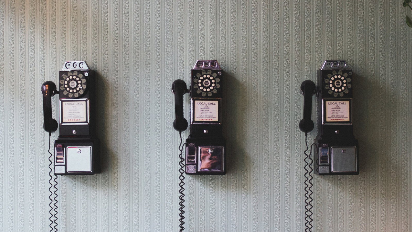 stock photo of three old telephones on wall