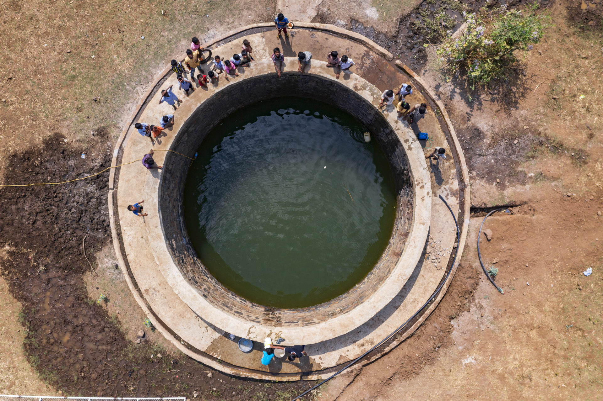 Aerial view of people surrounding water well in rural India