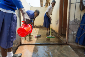 Tanzanian girls clean bathroom at their school