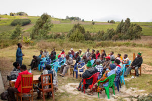 Tananizan people sit in a group and listen to presentation about agriculture