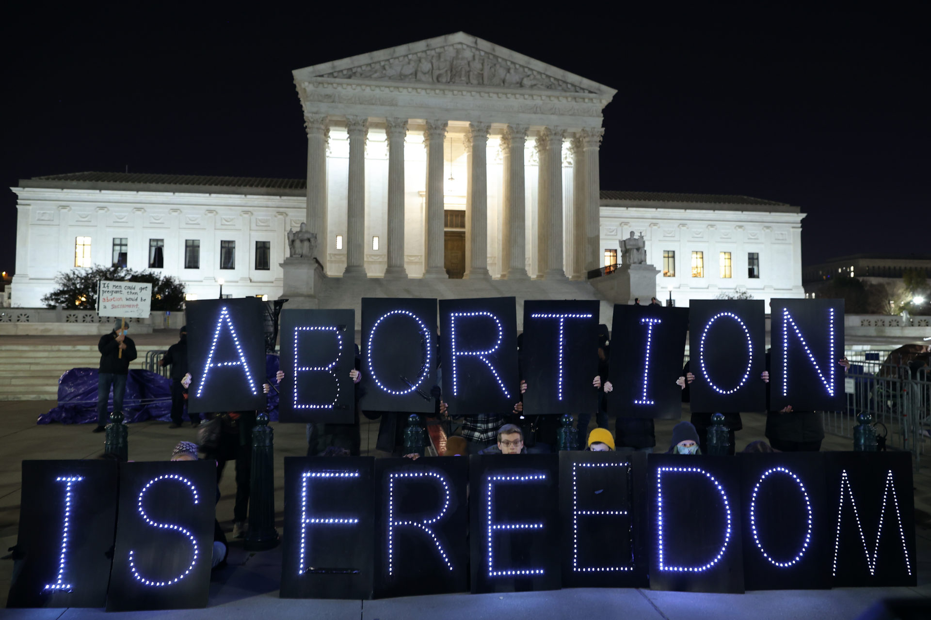 Abortion rights activists hold signs that spell "Abortion Is Freedom" in front of Supreme Court