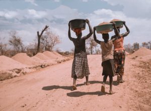 Three African women carrying grain