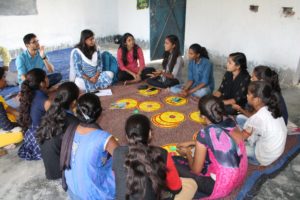 group of young people sit around communications materials developed by Population Foundation India