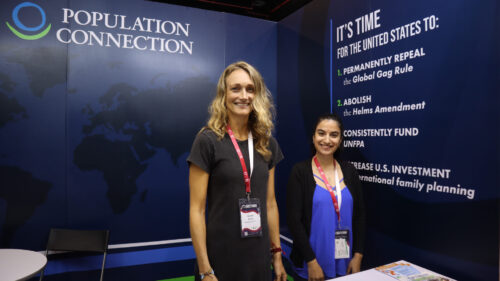 two women stand in exhibit booth