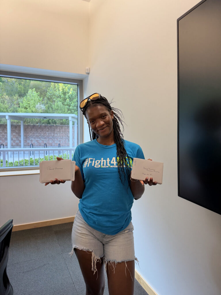 Richeline Cadet, wearing a #Fight4HER t-shirt, holds thank-you cards in both hands