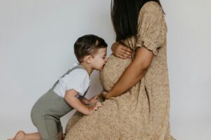 A pregnant woman with a small child who is kissing her belly