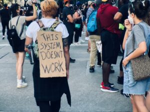 Young protesters in Houston. One person is carrying a sign that reads "This system doesn't work."